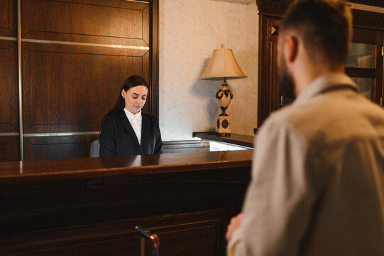 Hotel receptionist serving guest at reception desk
