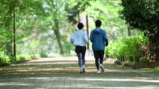 新緑の公園でウォーキングやランニングのスポーツが楽しいミドル夫婦の顔無しの後ろ姿全身　健康的（ヘルスケア）ライフスタイルのイメージ動画