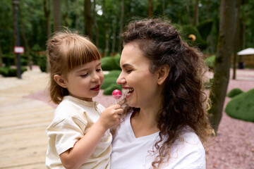 Fototapeta premium Joyful moments between a mother and daughter in a vibrant amusement park setting