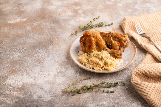 Fried Turkey Wing with spices and rice on brown concrete, side view, copy space