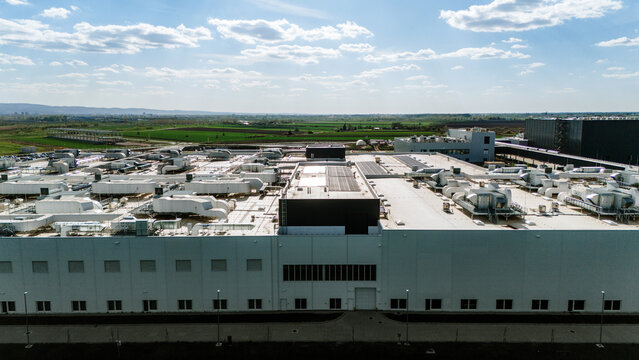 Aerial view of the expansive industrial complex, a symphony of white and grey against the backdrop of verdant fields and a boundless sky, Becej, Vojvodina, Serbia.