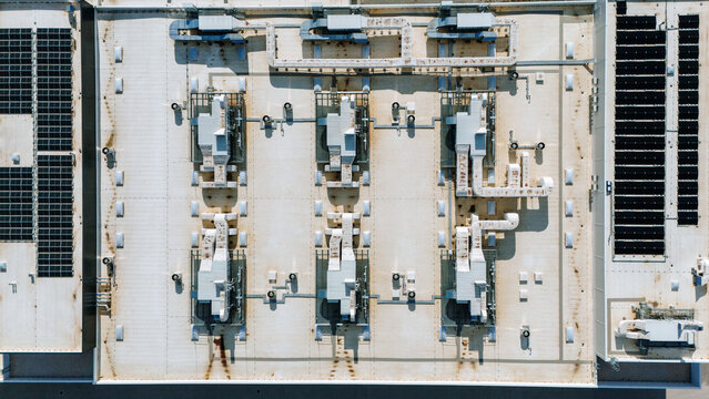 Aerial view of a flat rooftop adorned with mechanical equipment and solar panels under the bright sunlight, Becej, Vojvodina, Serbia.