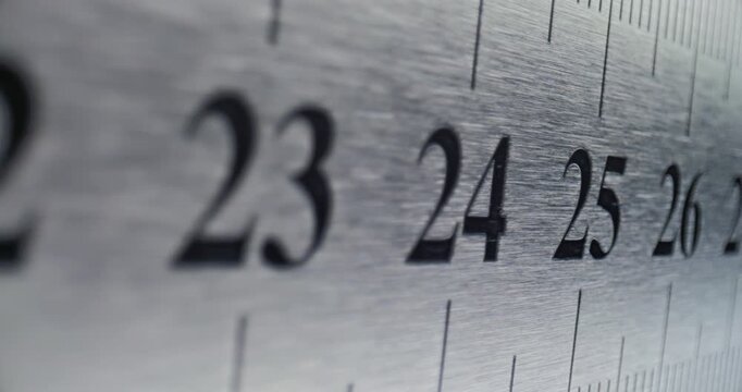 Slow Pan Over Metal Ruler. Smooth slow movement across extreme close-up of metallic ruler with black numbers and brushed surface.