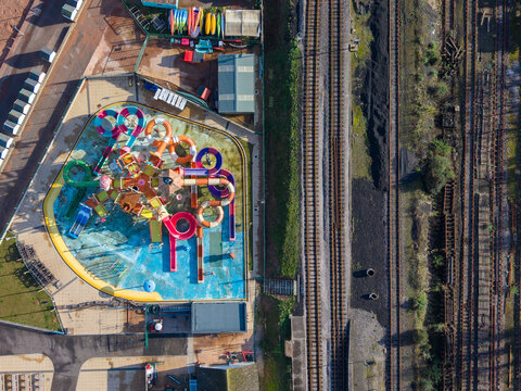 Aerial view of the contrasting vivid splash of the water park against the muted tones of the adjacent railway tracks, Paignton, England, United Kingdom.
