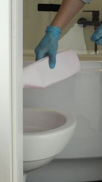 Woman pouring in detergent and cleaning the toilet with toilet brush close up. Cleaning at home, cleaner occupation, household chores, hygiene and disinfection at bathroom