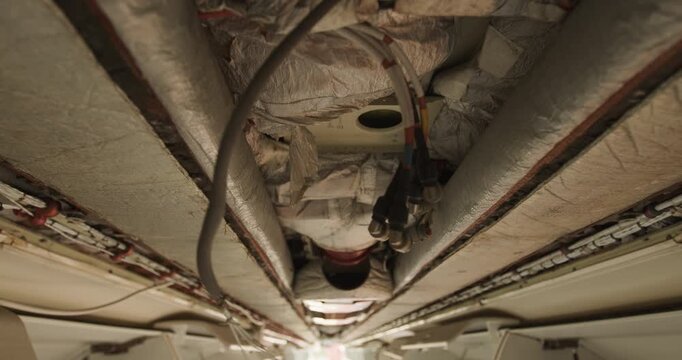 Low angle view of exposed wiring and insulation in the ceiling of a disassembled aircraft
