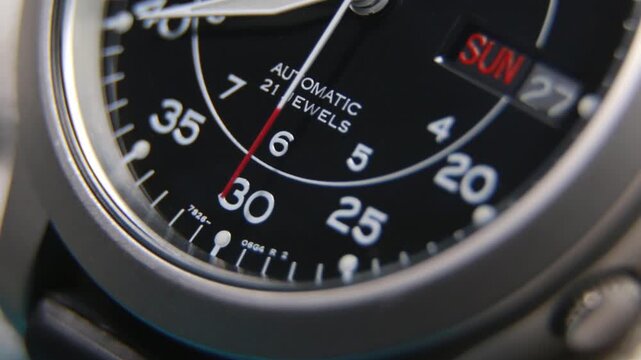 Macro close up of an automatic mechanical field watch with moving arms

