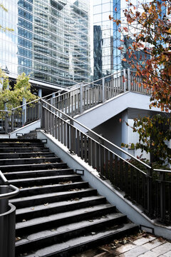 Stairs with handrail trace lines beside glass in urban finance architecture La Defense as autumn tones mark ascent in Paris France today