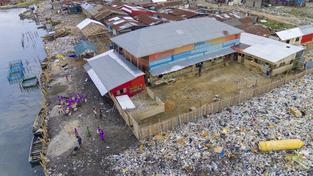 Aerial view of buildings amidst piles of discarded trash and debris, creating a stark contrast between human habitation and environmental degradation, Oworonshoki, Lagos, Nigeria.