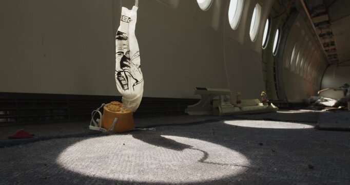 Interior view of a gutted aircraft cabin with sunlight hitting an oxygen mask on the floor