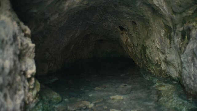 A dark cave with calm water and rugged rock formations creates a mysterious and cinematic atmosphere, evoking exploration and hidden natural spaces.