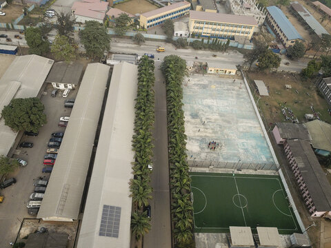 Aerial view of the contrasting textures of buildings and the neat rows of trees lining streets, casting shadows on the ground, Oworonshoki, Lagos, Nigeria.