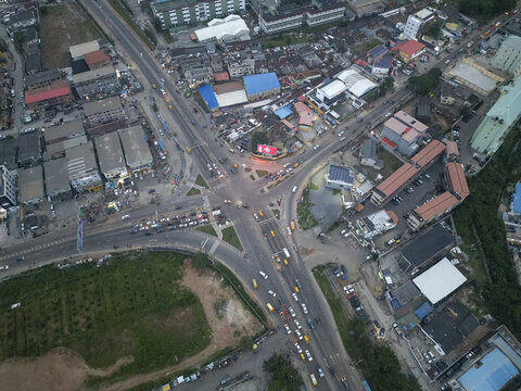 Aerial view of a bustling intersection in Ikeja, where vibrant yellow buses navigate the roads amidst buildings, Allen Avenue, Ikeja, Lagos, Nigeria.