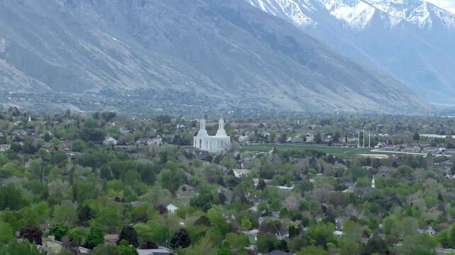 Lindon Utah Temple of the Church of Jesus Christ of Latter day Saints in Utah County USA within Utah Valley surrounded by residential area beneath Wasatch Range and Mount Timpanogos sliding aerial
