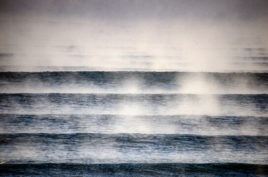 View of the ocean's misty breath shrouding the dark water surface in a ghostly veil, creating an ethereal scene of nature's raw beauty, Hossegor, France.
