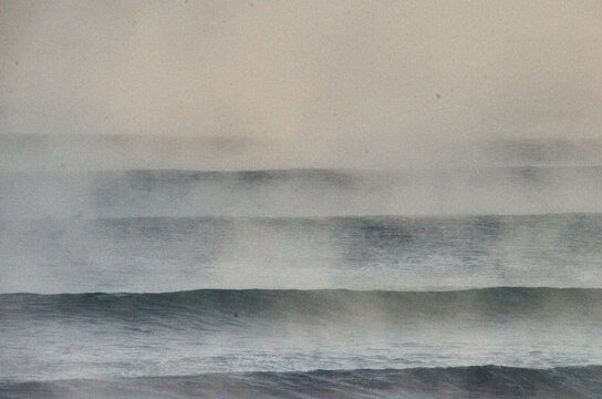 View of the cold, misty ocean waves rolling in with a mysterious fog hanging low over the water, creating an eerie atmosphere, Hossegor, France.