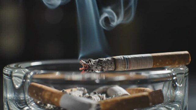 Burning Cigarette in Glass Ashtray with Rising Smoke