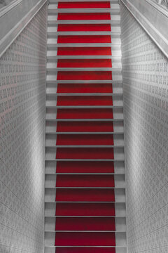 Sarajevo, Bosnia and Herzegovina - 07 May 2025: View of a vibrant red carpet cascading down a long staircase, flanked by cool grey tiled walls, creating a striking contrast in color and texture.