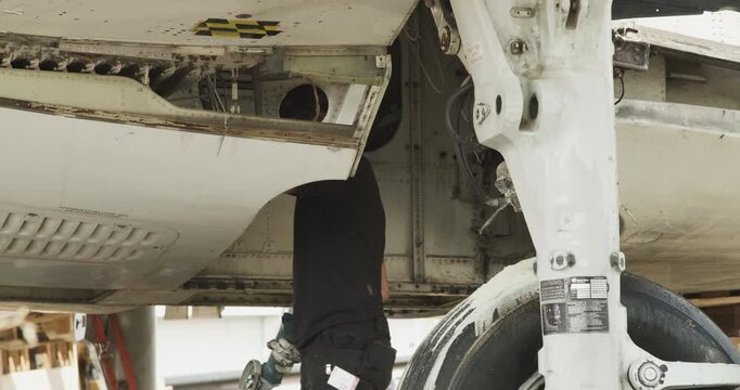 Person wearing safety mask using a power tool to grind the exterior metal surface of an aircraft fuselage
