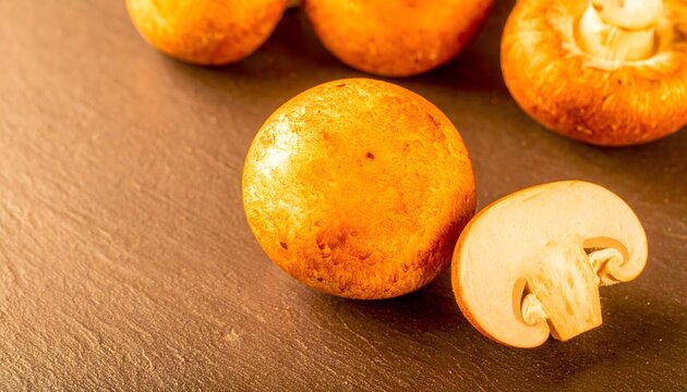 Champi&ntilde;ones enteros y cortado sobre superficie de madera con composici&oacute;n culinaria natural