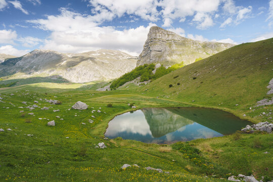 View of a tranquil alpine lake mirroring the towering peaks and verdant slopes of Zelengora, Foca, Republika Srpska, Bosnia and Herzegovina.