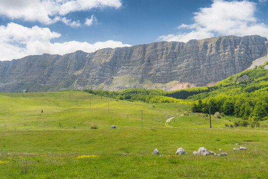 View of dramatic cliffs casting long shadows over the vibrant green meadows of Zelengora, Foca, Republika Srpska, Bosnia and Herzegovina.