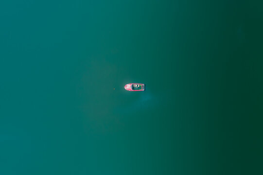 Aerial view of a lone boat resting on the glassy, turquoise water, a serene tableau of solitude and aquatic beauty, Cape Town, Western Cape, South Africa.