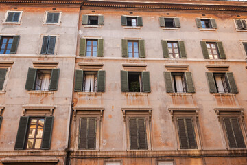 Obraz premium Historic residential facade with shuttered windows and aged plaster walls in Rome