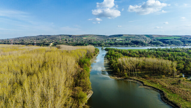 Aerial view of the meandering river splits the landscape into a tapestry of vibrant greens and yellows, with the distant hills adding depth, Krcedin, Vojvodina, Serbia.