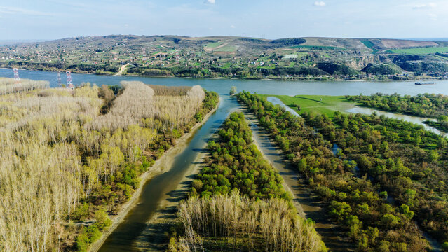 Aerial view of the Danube River winding through verdant landscapes, juxtaposing the bare trees with fresh greenery, Krcedin, Vojvodina, Serbia.