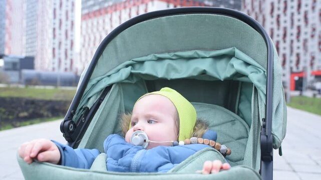 Adorable one year old baby boy pointing finger at camera in stroller