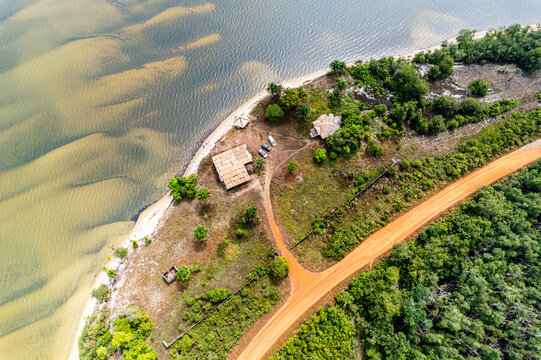Aerial view of the coastline where the red dirt road meets the sandy shore, contrasting with the clear blue sea, Monrovia, Monrovia, Liberia.