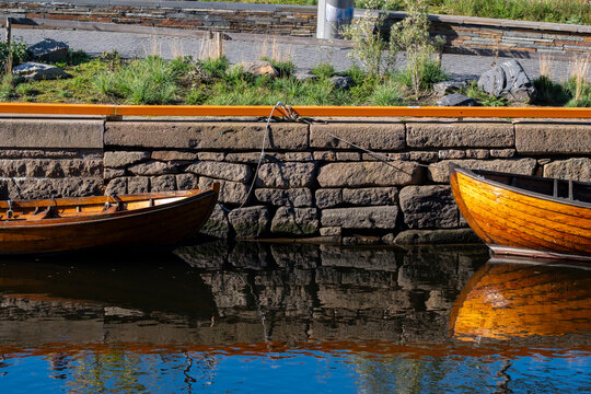 Quiet wooden boat mooring at Oslo waterfront harbor with calm reflection on Oslofjord fjord during golden autumn bright daylight in Norway
