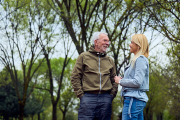 Fototapeta premium Older Man and Younger Woman Conversing Outdoors in Park Near Clinic During a Casual Spring Visit