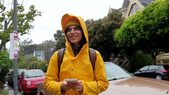 Woman in yellow raincoat using smartphone on san francisco street