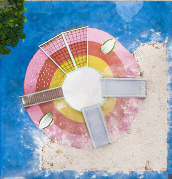 Aerial view of a playground featuring slides, climbing nets, and a sandpit with vibrant circular patterns and a blue surface in Taiwan.