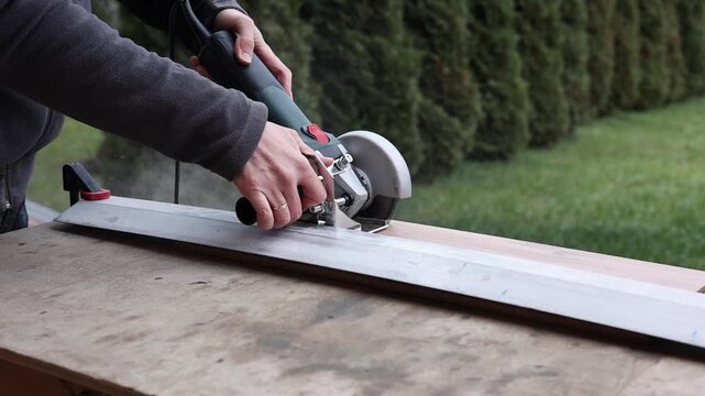 Man cutting a wooden board with a circular saw on an outdoor workbench, DIY home renovation, power tool construction work.