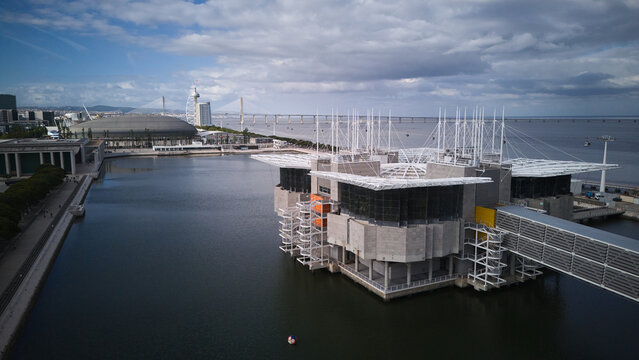 Aerial view of Oceanario de Lisboa building over Tagus river in Parque das Nacoes under a cloudy sky