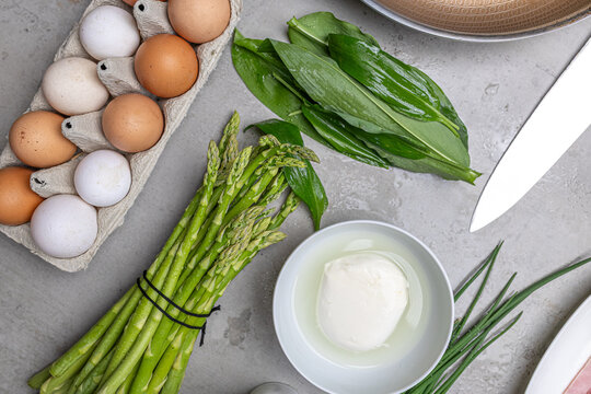 Cooking an italian frittata with mozarella, asparagus, eggs, onions, tomatoes and fresh herbs in spring time at home in the kitchen