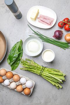 Cooking an italian frittata with mozarella, asparagus, eggs, onions, tomatoes and fresh herbs in spring time at home in the kitchen