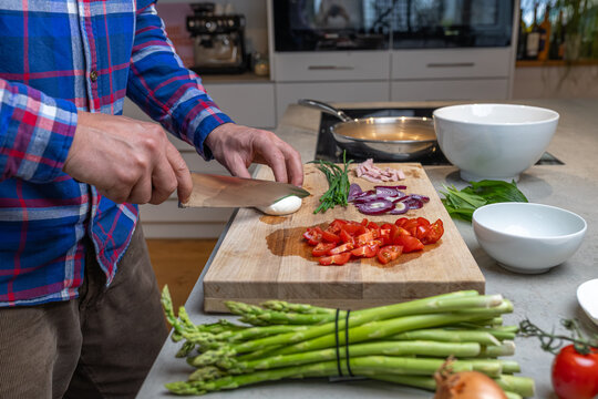 Cooking an italian frittata with mozarella, asparagus, eggs, onions, tomatoes and fresh herbs in spring time at home in the kitchen