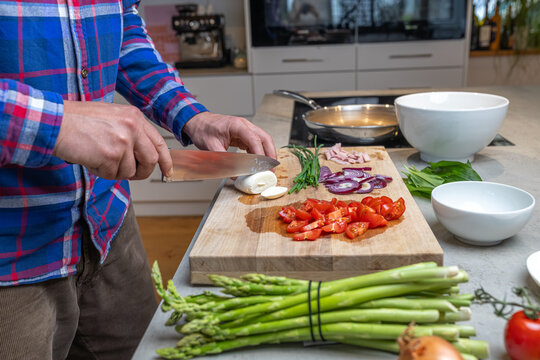 Cooking an italian frittata with mozarella, asparagus, eggs, onions, tomatoes and fresh herbs in spring time at home in the kitchen