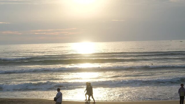 People walking by ocean at sunset Da Nang Vietnam beach waves golden light coastline