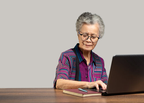 Elderly woman using laptop at home workspace