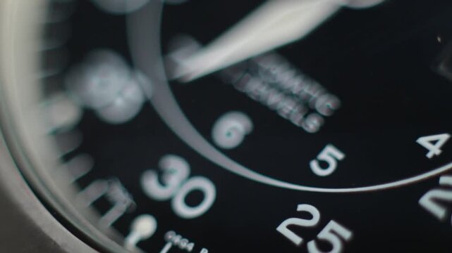 Macro close up of an automatic mechanical field watch with moving arms
