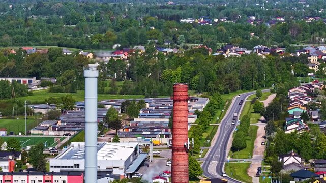Drone shot featuring factory smokestacks integrated into a suburban landscape with homes and roads.