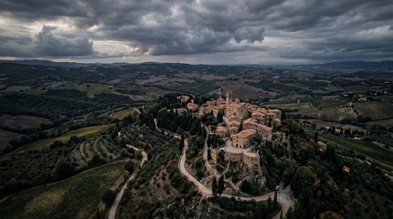Obraz premium Aerial View of a Medieval Tuscan Village Perched on a Hilltop Under Dramatic Clouds.