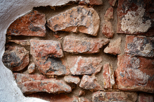 Rustic brickwork made of rough sandstone. Natural wall design with partial plastering. Vintage background texture. Close-up.