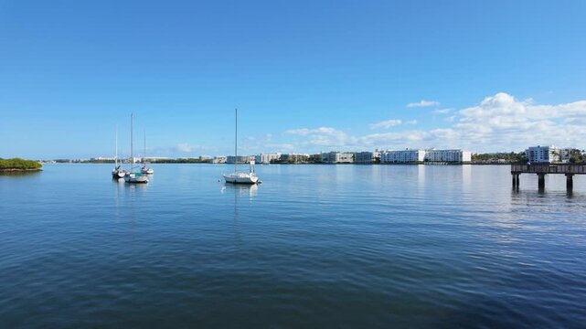 Slow pan from bridge over the ICW at Lake Worth Beach Florida toward Snook Island with moored boats, calm water, blue sky.