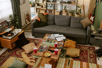 Wide angle shot of living room showing board game setup, snacks, vinyl player, scattered cups after gathering © AnnaStills